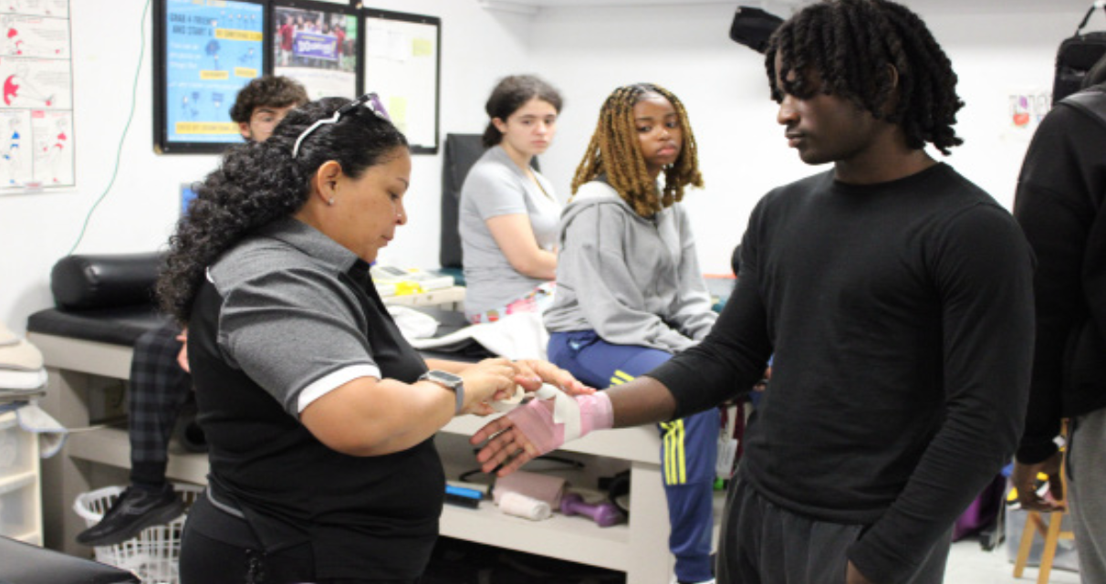 A HELPING HAND: Athletic trainer Julia Edwards helps wrap and bandage a
students hand.